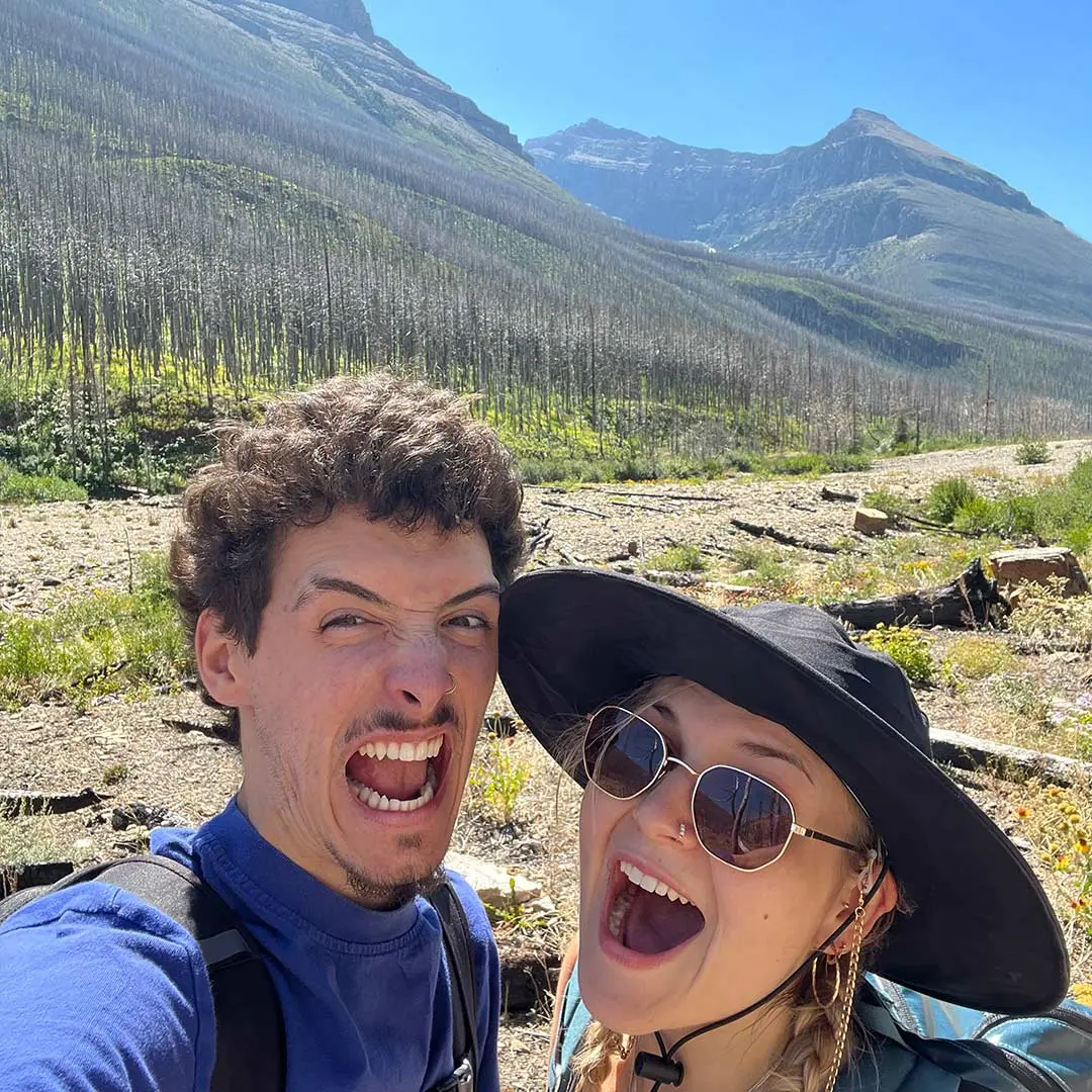 Guy and girl scream for camera in front of sunny mountains