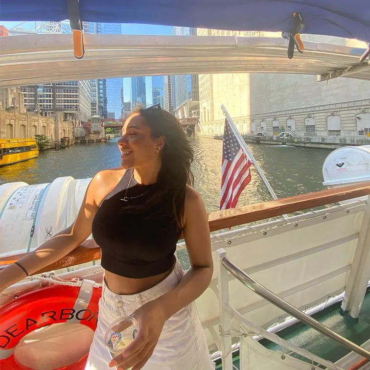 Girl on boat with USA flag behind her.