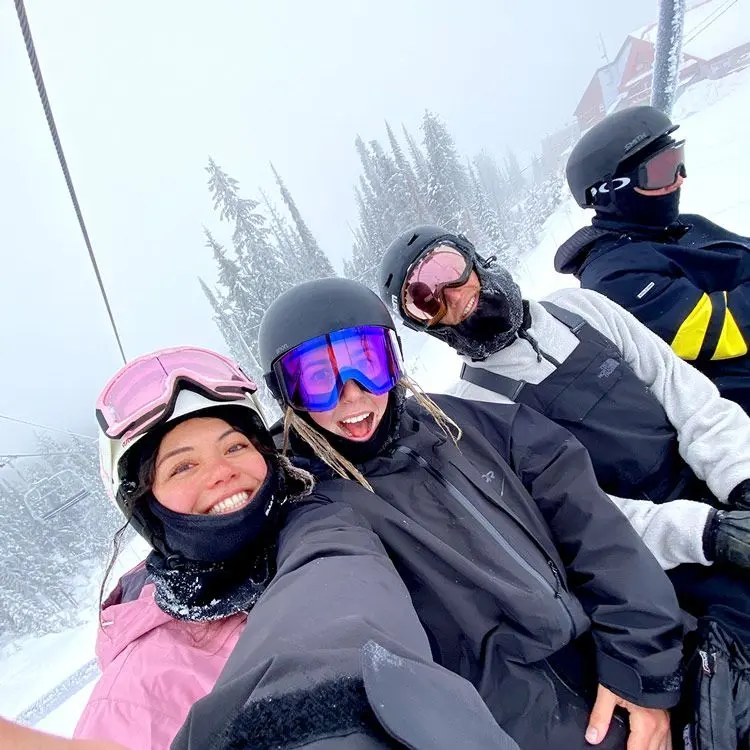 Friends sitting on ski lift pose for selfie