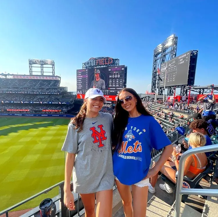 2 girls pose at a baseball game