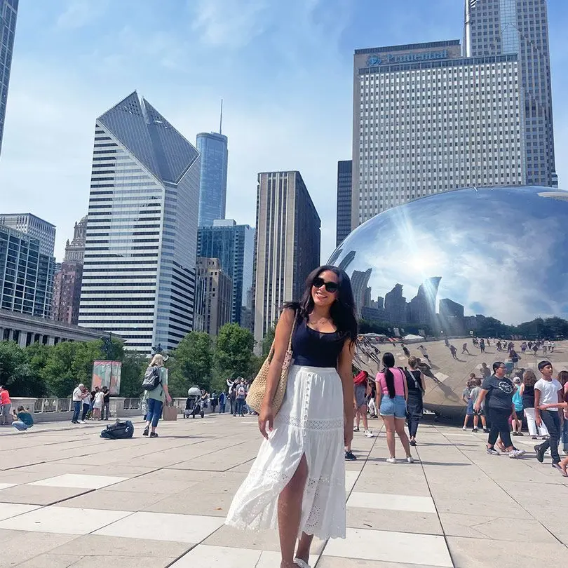 Girl with sunglasses smiles in front of Chicago monument on sunny day