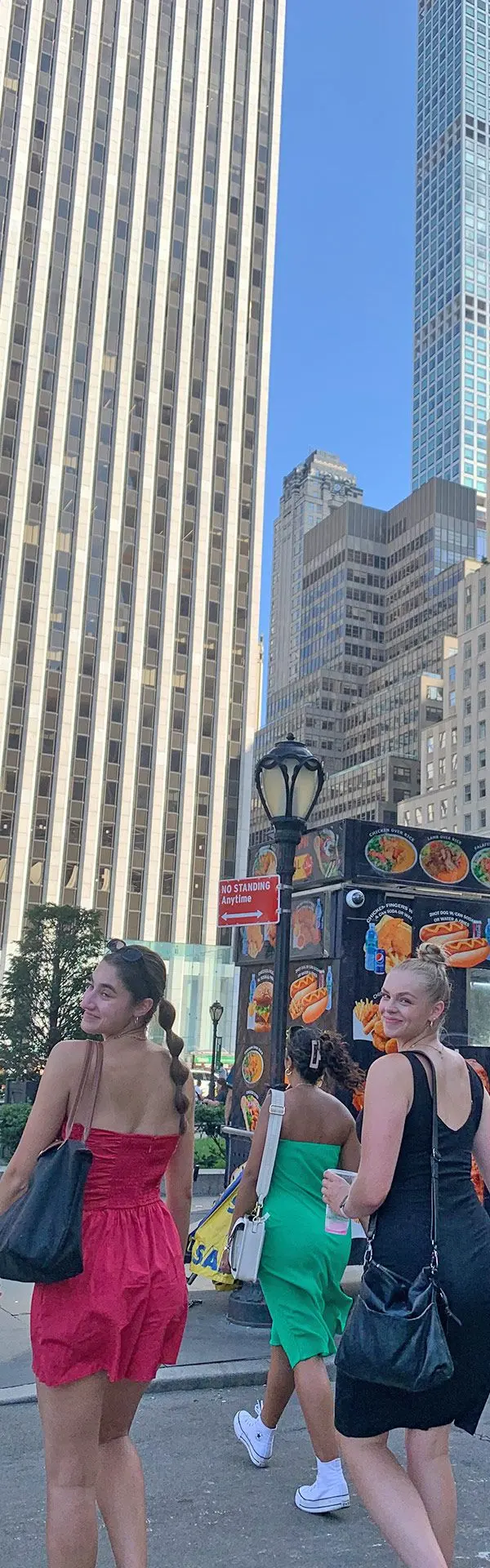 2 girls walk away from camera in big city on sunny day