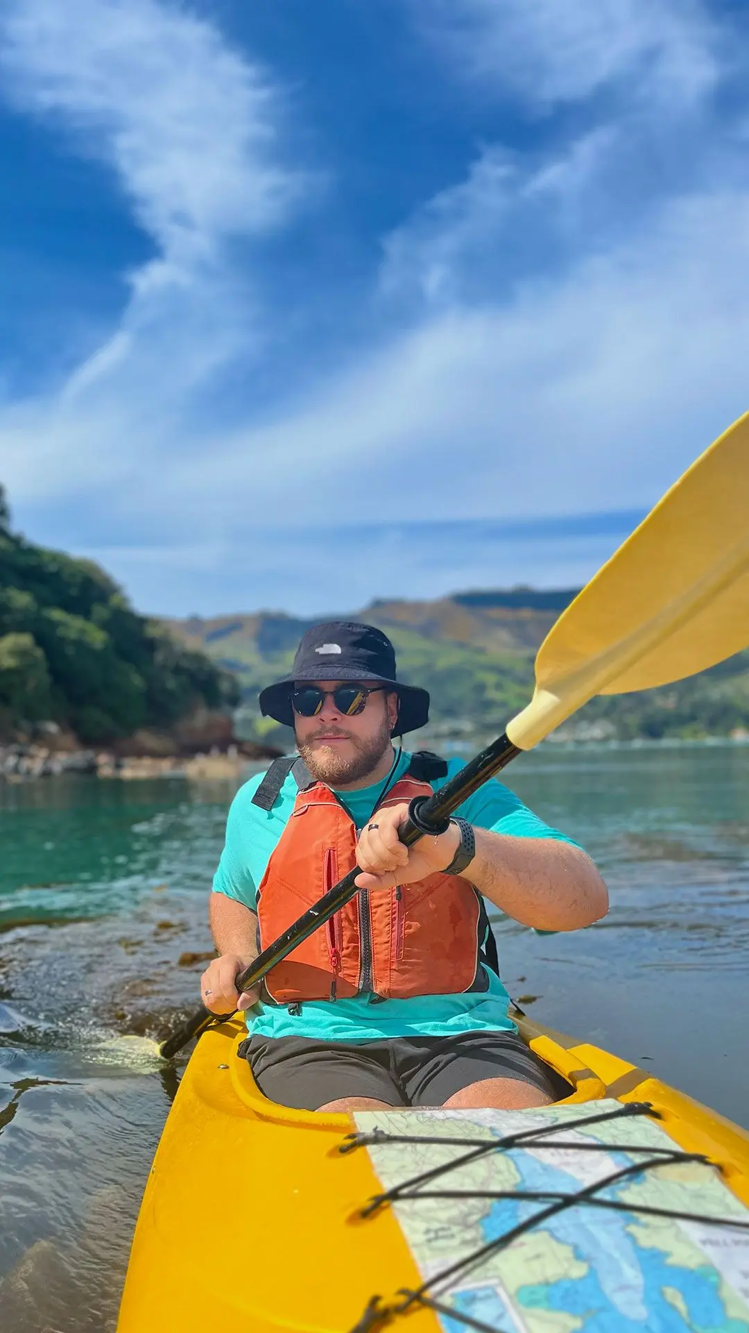 Guy on kayak in bay on sunny day wearing sunglasses